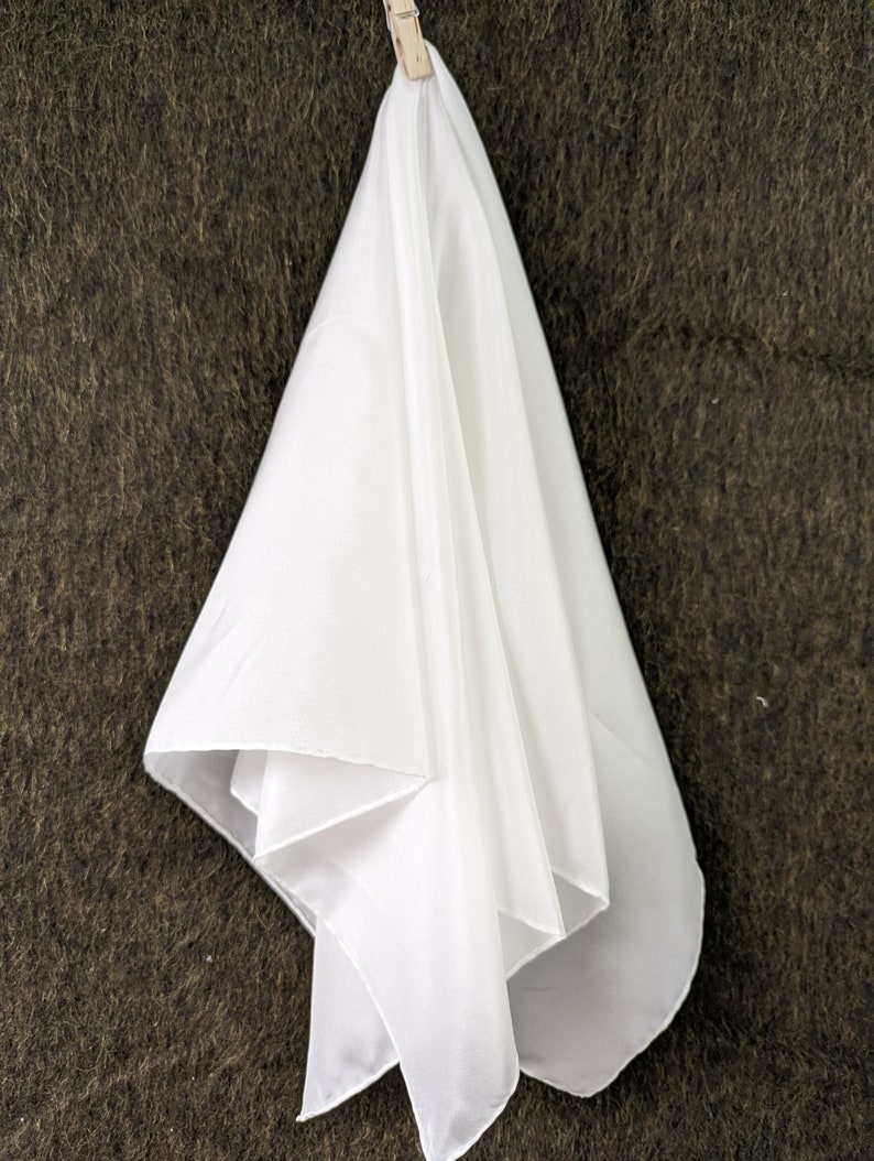 Pode incluir: Um len&ccedil;o de tecido branco e transparente pendurado em um fundo marrom texturizado.