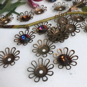 May include: A collection of small, gold-toned metal flower-shaped settings with a variety of iridescent glass stones in the center.
