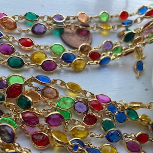 May include: A multi-strand necklace with oval-shaped, faceted glass beads in various colors. The beads are strung on a gold chain.