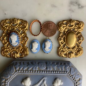 May include: A set of gold-toned metal embellishments with a cameo design. The set includes two oval frames, two blue cameo pendants, and a round frame. The cameo pendants feature a white profile of a woman on a blue background. The embellishments are perfect for adding a vintage touch to crafts and jewelry.