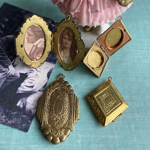 Könnte beinhalten: Fünf antike goldene Anhänger mit komplizierten Designs. Einige haben ovale Fenster mit verblassten Fotos darin. Ein Anhänger hat ein quadratisches Fenster.
