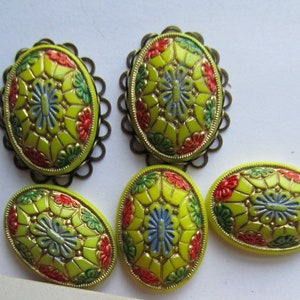 May include: Six oval-shaped yellow glass buttons with a floral design in red, green, and blue. The buttons have a gold-colored metal rim.