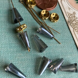 May include: A collection of grey glass cone-shaped beads with gold-toned metal bead caps and head pins.