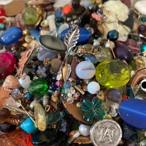 May include: A large collection of colorful beads, buttons, and other craft supplies. The assortment includes glass beads, metal beads, plastic beads, and more. There are also a variety of buttons, charms, and other decorative items.