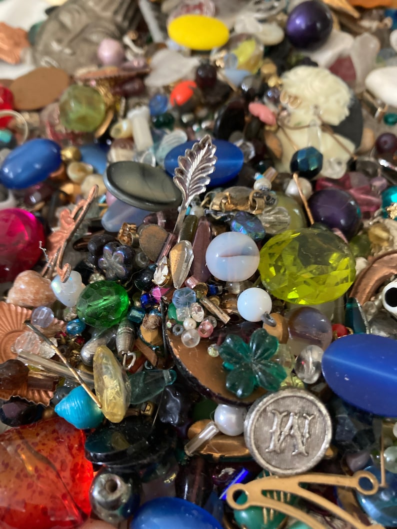 May include: A large collection of colorful beads, buttons, and other craft supplies. The assortment includes glass beads, metal beads, plastic beads, and more. There are also a variety of buttons, charms, and other decorative items.