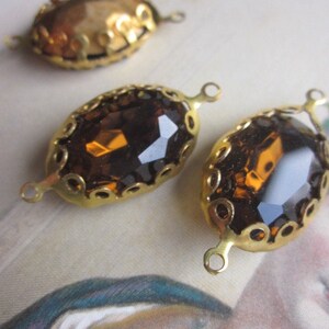 Pode incluir: Tr&ecirc;s enfeites de metal dourado com pedras de vidro &acirc;mbar de forma oval. Cada enfeite tem um design de filigrana decorativo e dois la&ccedil;os para prender a um projeto.
