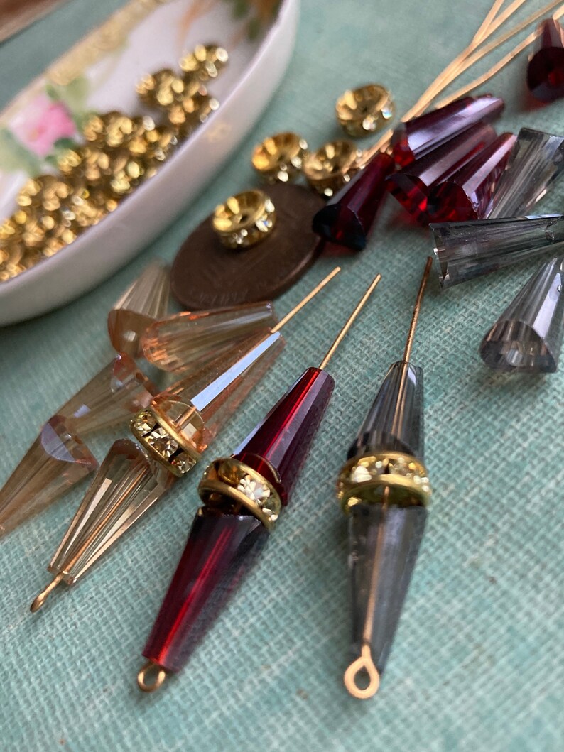 May include: Assortment of clear, red, and grey glass beads with gold accents. The beads are strung on gold wires and are ready to be used for jewellery making or other craft projects.