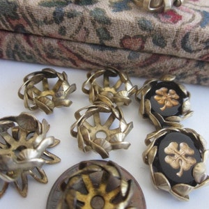 Puede incluir: Surtido de adornos decorativos de metal dorado y vidrio negro con un diseño de trébol de cuatro hojas. Algunos adornos tienen un diseño en relieve, de trabajo abierto, mientras que otros tienen un diseño plano y cerrado.