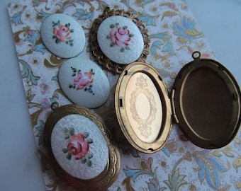 May include: Five oval-shaped antique lockets with floral designs. The lockets are made of metal with a white enamel background and painted floral designs. One locket is open, revealing a gold interior.