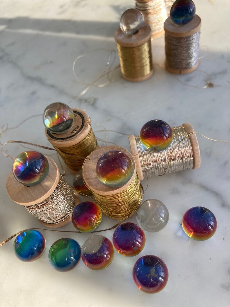 Peut inclure: Une collection de billes en verre iris&eacute;es sur des bobines de fil d'or et d'argent. Les billes sont de diff&eacute;rentes nuances de bleu, vert, rouge et orange.