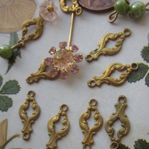 May include: Assortment of gold-tone metal embellishments with ornate designs. The embellishments have two holes for attaching to fabric or other materials.