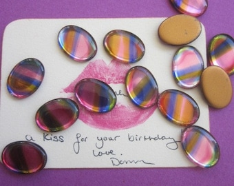 May include: A white card with a handwritten message that reads "a kiss for your birthday love.  Denn."  The card is decorated with iridescent oval-shaped glass gems in shades of pink, blue, and gold.