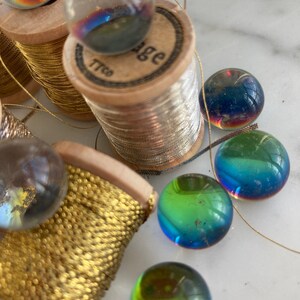 Peut inclure: Gros plan sur des bobines de fil d'or avec des billes de verre iris&eacute;es. Les bobines sont en bois et l'une d'elles porte l'inscription "Vintage".