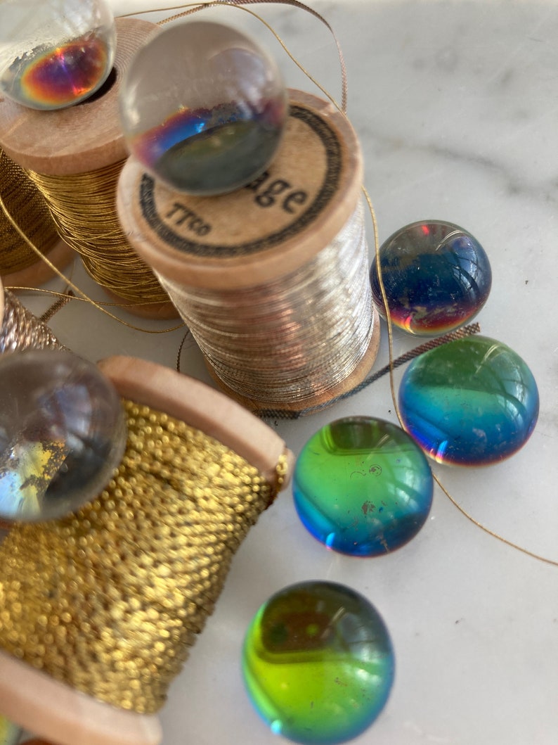 Peut inclure: Gros plan sur des bobines de fil d'or avec des billes de verre iris&eacute;es. Les bobines sont en bois et l'une d'elles porte l'inscription "Vintage".
