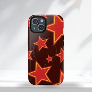 Peut inclure: Coque de téléphone avec un motif répété d'étoiles rouges bordées de jaune sur un fond marron foncé. L'étui est équipé d'une poignée pop-up intégrée. L'étui est conçu pour un smartphone.
