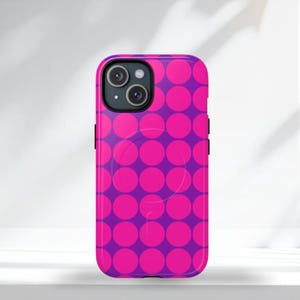 May include: A vibrant phone case featuring a repeating pattern of large, bright pink polka dots against a deep purple background. The case has a glossy finish and is designed to fit a smartphone, with cutouts for the camera and buttons.