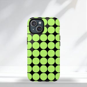 Op de afbeelding: Een zwart-groene telefoonhoes met een herhalend patroon van limoengroene cirkels. De telefoonhoes heeft een camera-uitsparing en zwarte zijknoppen. De hoes ligt op een wit oppervlak.