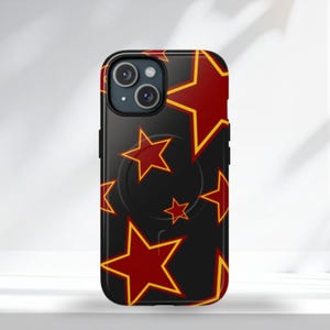 Op de afbeelding: Zwarte telefoonhoes met een patroon van rode sterren met gele omtreklijnen. De hoes heeft een ingebouwde zwarte pop-up grip. De telefoonhoes is ontworpen voor een smartphone.