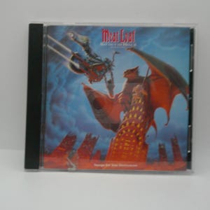 May include: A CD case featuring the album "Bat Out of Hell II" by Meat Loaf. The cover art depicts a motorcycle rider in flight, a large red winged creature, and a cityscape against a blue sky. The album title is in red.