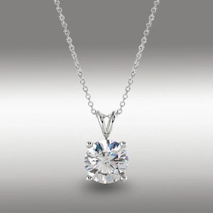 May include: A silver-toned necklace featuring a single round, clear, faceted gemstone pendant held in a four-prong setting. The pendant is suspended from a delicate, thin silver-toned chain with small, uniform circular links that connect to the top.