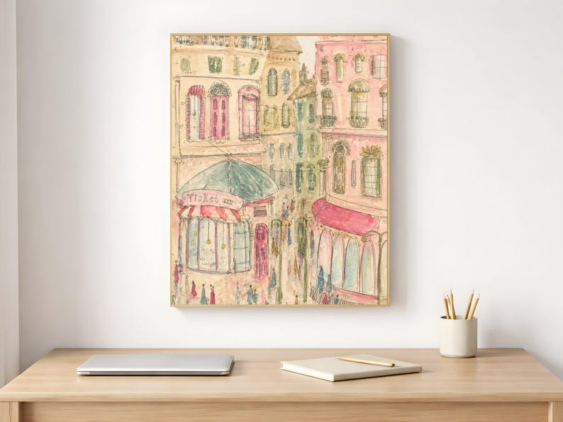 Framed Parisian watercolor print styled on a white desk beside a laptop and minimal stationery in a bright home office