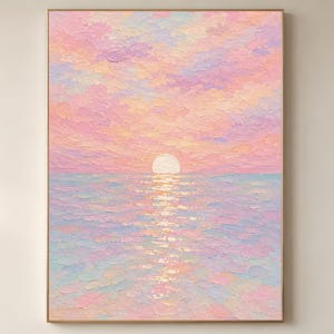 May include: A framed painting of a sunset over the sea. The sky is a mix of pink, peach, and lavender, with the sun as a bright white circle. The water mirrors the sky's colours, creating a tranquil and colourful seascape.