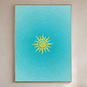 May include: A framed artwork featuring a vibrant yellow sun design against a gradient turquoise background. The sun is centrally positioned, radiating stylized rays. The artwork is encased in a gold-colored frame, suitable for wall decor.