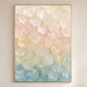 Puede incluir: Una pieza de arte mural rectangular con un patrón superpuesto en forma de escamas hecho de discos circulares de concha translúcidos. La composición muestra un degradado vertical, desde crema suave y rosa pálido arriba hasta azul claro en la base.