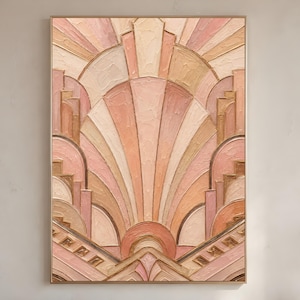 May include: A framed art deco style painting with a geometric design in shades of peach, beige, and gold. The artwork features a sunburst pattern with layered shapes and lines, creating a textured effect. The frame is a thin, gold color.