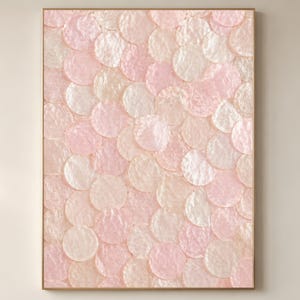 Könnte beinhalten: Gerahmtes Kunstwerk mit einem Muster aus sich überlappenden, kreisförmigen Formen. Die Kreise sind in Rosa-, Creme- und Weißtönen gehalten und erzeugen einen strukturierten Effekt. Der Rahmen ist hellbraun.