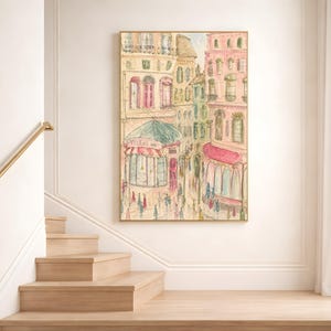 Parisian street scene watercolor print displayed on a white wall above a staircase landing in a bright minimal interior