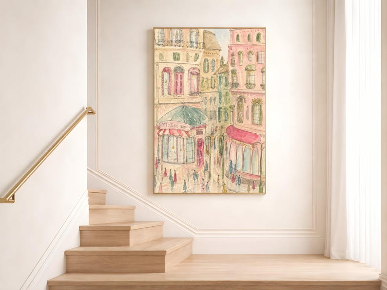 Parisian street scene watercolor print displayed on a white wall above a staircase landing in a bright minimal interior