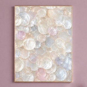 May include: A rectangular wall art piece featuring a dense, layered composition of translucent, circular, iridescent discs in shades of cream, pale pink, and soft blue, all encased within a thin, metallic gold frame with a reflective finish.