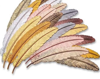 May include: A collection of metal feather-shaped bookmarks arranged in a fan pattern. The set includes various metallic finishes such as gold, silver, rose gold, copper, and bronze, each featuring detailed etched lines mimicking natural feather textures.