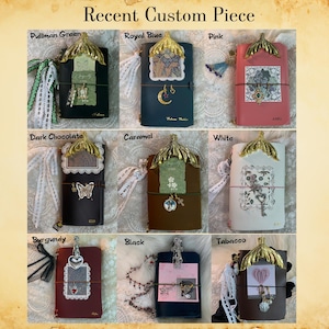 May include: A collection of custom leather journals in various colors, including green, blue, pink, dark chocolate, caramel, white, burgundy, black, and tobacco. Each journal features a decorative gold accent and unique embellishments.