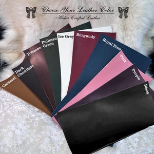 May include: A fan of leather swatches in various colors, including caramel, dark chocolate, tobacco, and burgundy. Other colors include ice grey, royal blue, pink, purple, and black. The text "Choose Your Leather Color" and "Hidea Crafted Leather" is visible.