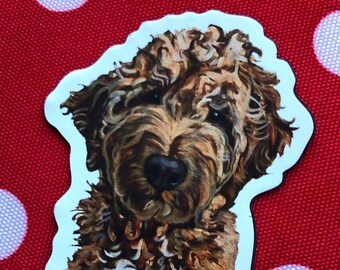 Könnte beinhalten: Ein Aufkleber mit einer handgemalten Illustration eines braunen und weißen lockigen Hundes. Der Hund schaut den Betrachter direkt an und hat einen verspielten Ausdruck.