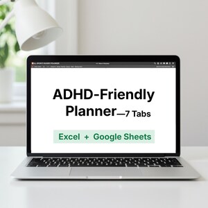 May include: A laptop displays the text "ADHD-Friendly Planner - 7 Tabs" in a bold, black font. Below, the text "Excel + Google Sheets" is in a green box. The laptop is open on a white surface, with a white lamp in the background.