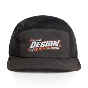 May include: A black five-panel cap featuring a central graphic with the text YOUR DESIGN HERE in white and orange lettering, accented by a small checkered flag pattern and star icons on a dark gray front panel.