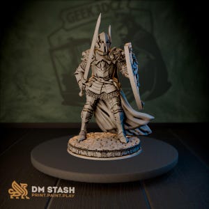 Op de afbeelding: Een gedetailleerde, grijze miniatuur van een ridder in volledige wapenrusting, met een zwaard en schild. De ridder staat op een cirkelvormige basis met een textuurontwerp. De figuur heeft een helm en een vloeiende cape. De basis heeft de tekst "DM STASH PRINT.PAINT.PLAY".