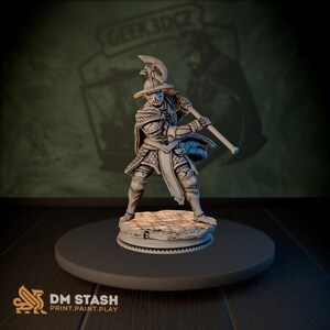 Op de afbeelding: Een gedetailleerde, grijze miniatuurfiguur van een middeleeuwse krijger, die een grote bijl vasthoudt. De figuur is gekleed in een harnas en staat op een stenen voet. De figuur staat op een donkergrijs cirkelvormig platform. De tekst "DM STASH PRINT.PAINT.PLAY" is zichtbaar.