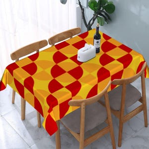 May include: A rectangular tablecloth featuring a repeating geometric pattern of interlocking circles and semicircles in vibrant shades of yellow, orange, and red, draped over a wooden table with four matching wooden chairs.