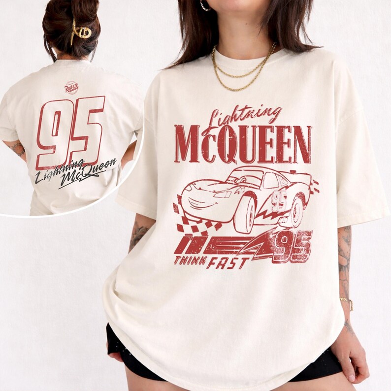 May include: Cream-coloured t-shirt with a red graphic of Lightning McQueen and the number 95. The front of the shirt displays the car and text, while the back has a large 95 and the Lightning McQueen logo.
