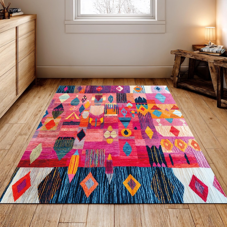 May include: A colourful rectangular rug with a patchwork design. The rug features geometric shapes in pink, red, blue, orange, and yellow. The rug is placed on a wooden floor in a room with natural light. The rug measures approximately 200cm x 300cm.