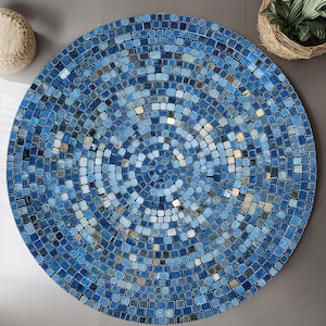 Può includere: Un piano del tavolo rotondo a mosaico con un design concentrico in tonalità di blu, bianco e grigio. Il mosaico è composto da piccole tessere quadrate. Il piano del tavolo è un elemento decorativo per un patio o uno spazio interno.