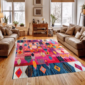 May include: A colourful, rectangular rug with a geometric pattern. The rug features pink, blue, orange, and yellow. Diamond and abstract shapes are prominent, creating a bold statement piece for a living room. The rug is approximately 200cm x 300cm.
