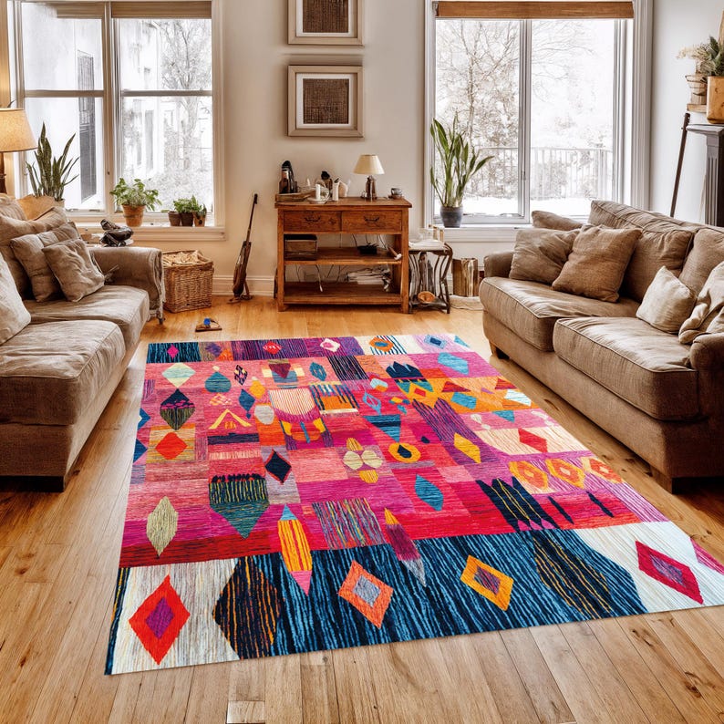 May include: A colourful, rectangular rug with a geometric pattern. The rug features pink, blue, orange, and yellow. Diamond and abstract shapes are prominent, creating a bold statement piece for a living room. The rug is approximately 200cm x 300cm.