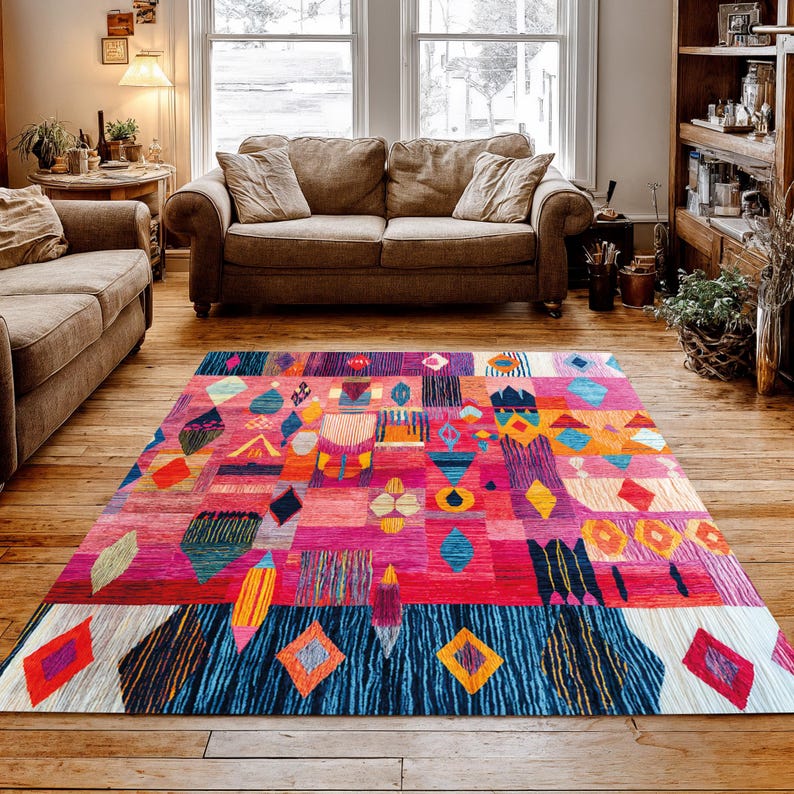 May include: A colourful, geometric area rug with a patchwork design. The rug features a mix of colours including pink, red, blue, orange, and purple. Diamond, rectangle, and triangle shapes are incorporated into the design, creating a bold statement piece.