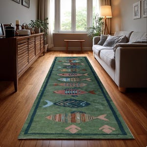 May include: A green rectangular rug with a dark blue border and a repeating pattern of colourful fish. The fish designs include shades of red, blue, orange, and pink. The rug is placed on a hardwood floor in a living room setting.