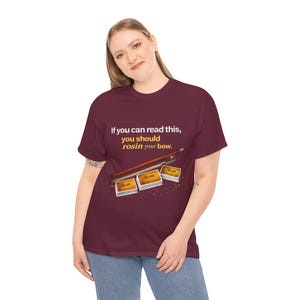 Könnte beinhalten: Burgunderfarbenes T-Shirt mit dem Text "If you can read this, you should rosin your bow." Das Shirt zeigt eine Abbildung eines Geigenbogens und drei Kolophonium-Boxen. Das Shirt wird von einer Person getragen.